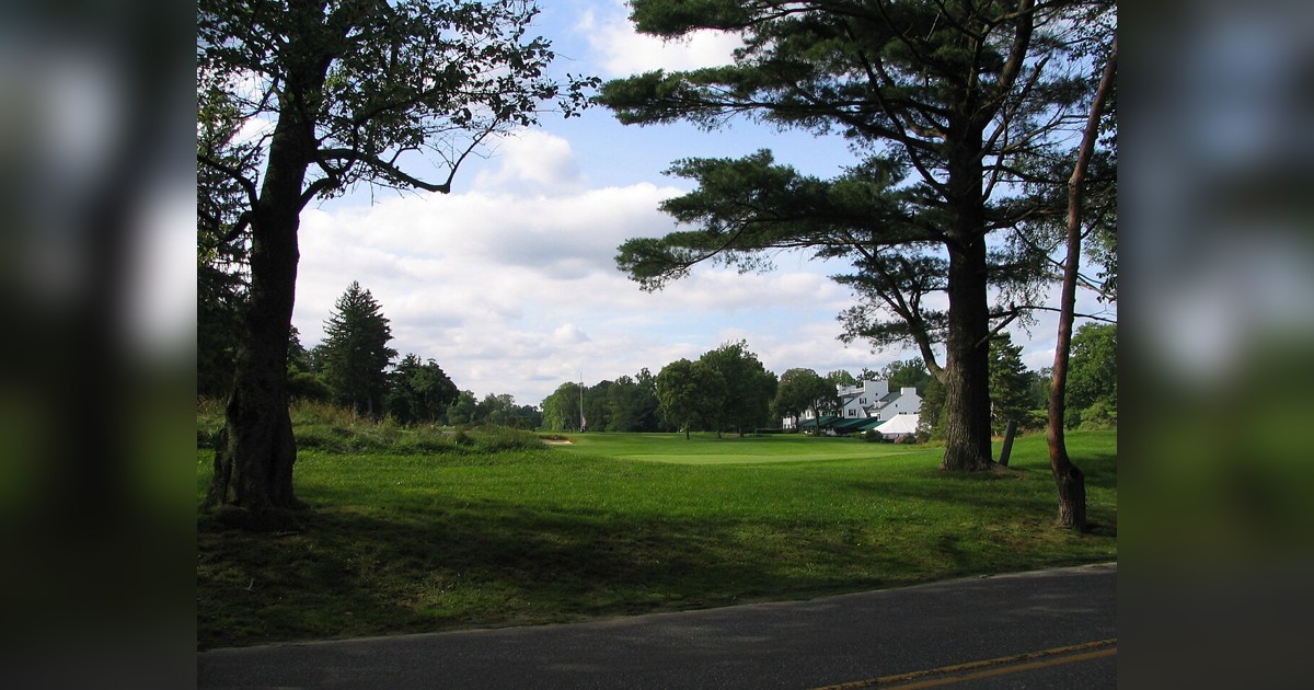 Historic stone marker at Merion Golf Club surrounded by trees